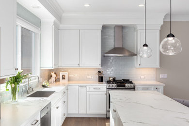 Large transitional l-shaped light wood floor open concept kitchen photo in San Francisco with an undermount sink, shaker cabinets, white cabinets, quartz countertops, white backsplash, ceramic backsplash, stainless steel appliances, an island and white countertops
