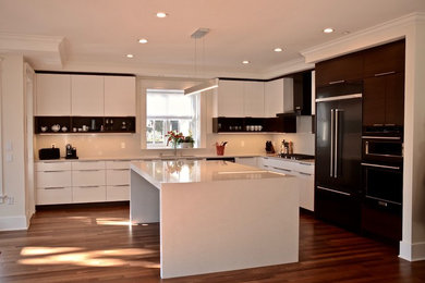 This is an example of a large modern l-shaped open plan kitchen in Other with an undermount sink, flat-panel cabinets, white cabinets, solid surface benchtops, grey splashback, stone slab splashback, stainless steel appliances, dark hardwood floors, with island, brown floor and grey benchtop.