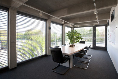 Großes Modernes Arbeitszimmer ohne Kamin mit Arbeitsplatz, grauer Wandfarbe, Teppichboden, freistehendem Schreibtisch und grauem Boden in Berlin
