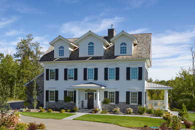 Aménagement d'une façade de maison blanche campagne de taille moyenne et à un étage avec un toit à deux pans et un toit mixte.