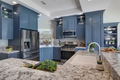 Photo of a mid-sized transitional kitchen in Orange County with a double-bowl sink, shaker cabinets, blue cabinets, quartz benchtops, beige splashback, ceramic splashback, stainless steel appliances, porcelain floors, brown floor and beige benchtop.