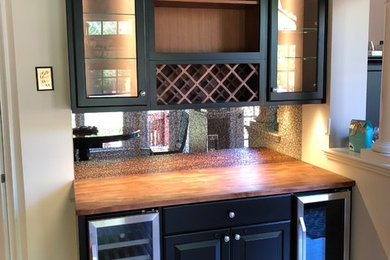 Inspiration for a small modern single-wall medium tone wood floor and brown floor wet bar remodel in Charlotte with glass-front cabinets, black cabinets, mirror backsplash and brown countertops