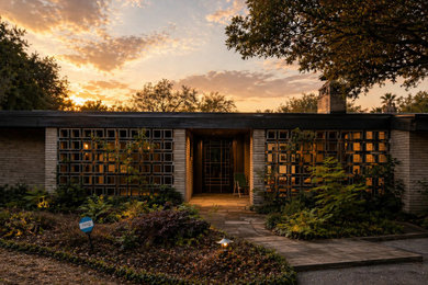 Inspiration for a mid-sized mid-century modern beige one-story brick house exterior remodel in Austin with a shed roof, a shingle roof and a gray roof
