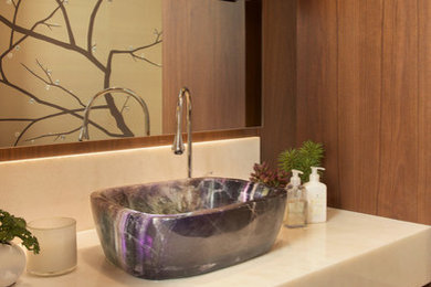 Large trendy dark wood floor and brown floor powder room photo in Denver with flat-panel cabinets, medium tone wood cabinets, a one-piece toilet, beige walls, a vessel sink and onyx countertops
