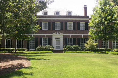 Huge elegant red two-story brick house exterior photo in Atlanta with a clipped gable roof