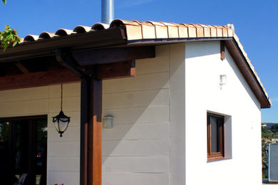 Diseño de fachada blanca de estilo de casa de campo pequeña de una planta con revestimiento de aglomerado de cemento y tejado a dos aguas