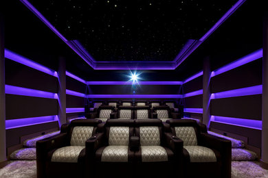 This is an example of a mid-sized modern enclosed home theatre in New York with purple walls, carpet, beige floor and a built-in media wall.