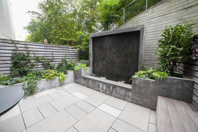 Photo of a mid-sized modern backyard and ground level deck in New York with a water feature, no cover and wood railing.