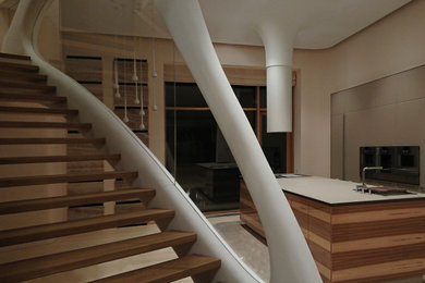 На фото: изогнутая лестница среднего размера в современном стиле с деревянными ступенями и перилами из смешанных материалов