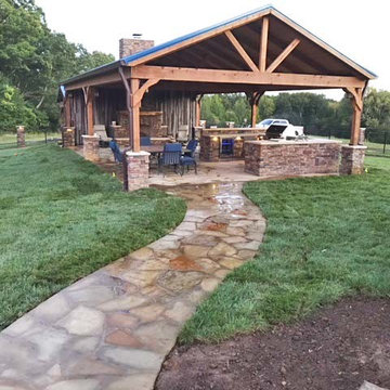 Flagstone walkway to covered pavilion with outdoor kitchen and fireplace.