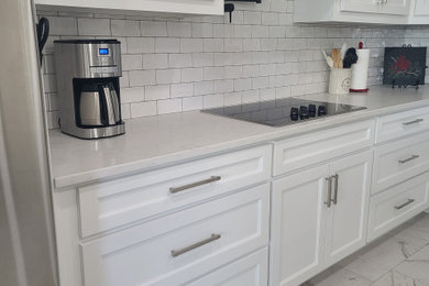 Kitchen - large transitional porcelain tile and multicolored floor kitchen idea in Dallas with shaker cabinets, white cabinets, white backsplash, ceramic backsplash, stainless steel appliances, an island and white countertops