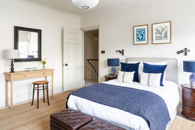 This is an example of a transitional bedroom in London with white walls.