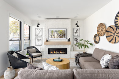 Large contemporary open concept living room in Vancouver with white walls, light hardwood floors, a standard fireplace, a brick fireplace surround and a wall-mounted tv.