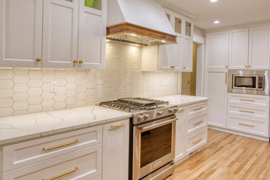 Example of a large classic u-shaped medium tone wood floor and brown floor open concept kitchen design in Portland with an undermount sink, shaker cabinets, white cabinets, quartz countertops, white backsplash, ceramic backsplash, stainless steel appliances, an island and white countertops