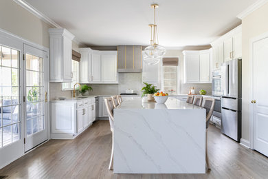 Inspiration for a transitional u-shaped medium tone wood floor kitchen remodel in Charlotte with an undermount sink, raised-panel cabinets, quartzite countertops, white backsplash, stainless steel appliances, an island and white countertops