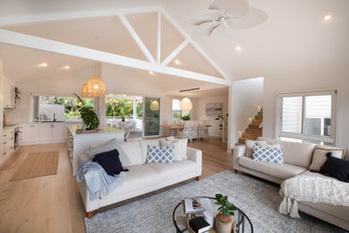 Design ideas for a large beach style living room in Sydney with white walls, light hardwood floors and exposed beam.