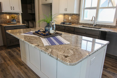 Eat-in kitchen - mid-sized transitional l-shaped laminate floor and brown floor eat-in kitchen idea in Minneapolis with an undermount sink, shaker cabinets, white cabinets, granite countertops, gray backsplash, ceramic backsplash, an island and multicolored countertops