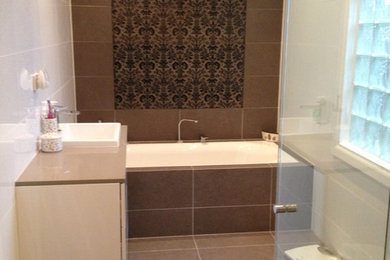Inspiration for a modern bathroom in Sydney with a drop-in tub, brown tile, porcelain tile and porcelain floors.