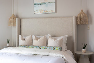 Modelo de dormitorio principal y abovedado marinero con paredes beige, papel pintado, suelo de madera oscura y suelo marrón