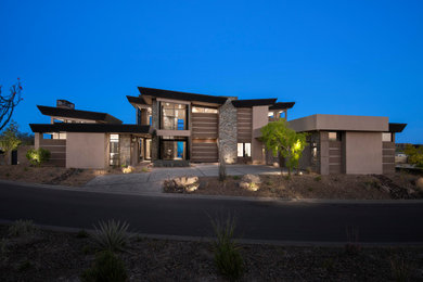 Example of a huge minimalist three-story stone house exterior design in Phoenix with a butterfly roof