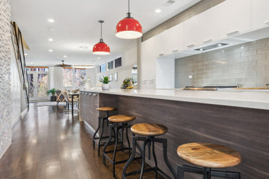 Inspiration for a large contemporary galley dark wood floor and brown floor open concept kitchen remodel in Chicago with an undermount sink, flat-panel cabinets, dark wood cabinets, quartz countertops, gray backsplash, glass tile backsplash, paneled appliances, an island and white countertops