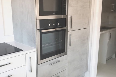 Medium sized contemporary u-shaped kitchen/diner in Other with a submerged sink, flat-panel cabinets, limestone worktops, laminate floors, a breakfast bar and white floors.