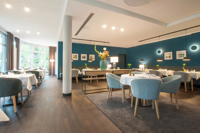 Modernes Esszimmer ohne Kamin mit blauer Wandfarbe, dunklem Holzboden und braunem Boden in Berlin