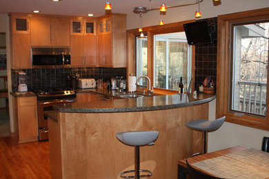 This is an example of a small contemporary u-shaped separate kitchen in Minneapolis with flat-panel cabinets, stainless steel cabinets, granite benchtops, grey splashback, porcelain splashback, stainless steel appliances, medium hardwood floors, no island and brown floor.