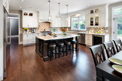 This is an example of a large mediterranean l-shaped eat-in kitchen in Ottawa with an undermount sink, raised-panel cabinets, white cabinets, granite benchtops, multi-coloured splashback, mosaic tile splashback, stainless steel appliances, dark hardwood floors, with island and brown floor.