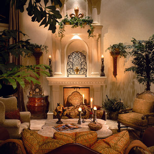 Modelo de salón para visitas cerrado, mediterráneo, de tamaño medio, sin televisor, con paredes beige, chimenea tradicional, suelo de travertino, marco de chimenea de yeso y suelo beige