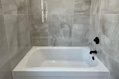 Diseño de cuarto de baño principal minimalista grande con bañera empotrada, baldosas y/o azulejos grises, baldosas y/o azulejos de porcelana, paredes grises, suelo de baldosas de porcelana y suelo gris
