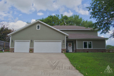 Large green two-story vinyl house exterior photo in Other with a shingle roof