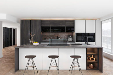 This is an example of a large modern grey and brown single-wall open plan kitchen in London with an integrated sink, flat-panel cabinets, dark wood cabinets, engineered stone countertops, brown splashback, stone slab splashback, black appliances, medium hardwood flooring, an island, brown floors and brown worktops.