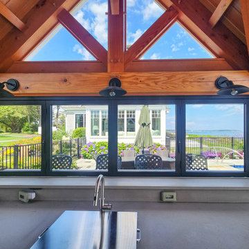 Counter and Sink Sit Beneath a Folding Glass Window Over the Pool Deck