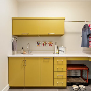 Design ideas for a contemporary l-shaped separated utility room in Other with a submerged sink, flat-panel cabinets, yellow cabinets, white walls, a stacked washer and dryer, grey floors and white worktops.