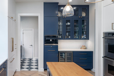 Eat-in kitchen - mid-sized contemporary u-shaped light wood floor and beige floor eat-in kitchen idea in Austin with an undermount sink, flat-panel cabinets, blue cabinets, quartz countertops, white backsplash, ceramic backsplash, stainless steel appliances, an island and white countertops