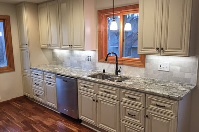 Eat-in kitchen - mid-sized traditional galley dark wood floor and brown floor eat-in kitchen idea in Minneapolis with a double-bowl sink, raised-panel cabinets, light wood cabinets, granite countertops, gray backsplash, marble backsplash, stainless steel appliances and no island