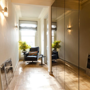 Klassisk inredning av en mellanstor hall, med grå väggar, ljust trägolv och beiget golv