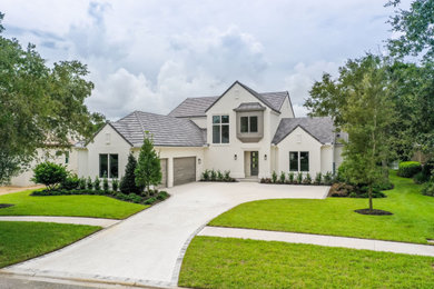 Large transitional white two-story stucco and board and batten exterior home idea in Jacksonville with a tile roof and a gray roof