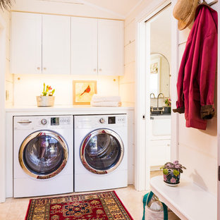 Design ideas for a mid-sized transitional single-wall utility room in Burlington with a side-by-side washer and dryer, shaker cabinets, white cabinets, solid surface benchtops, white walls and travertine floors.