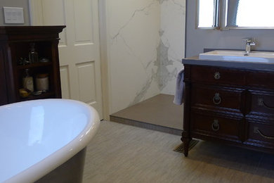 Large transitional master bathroom in Indianapolis with a drop-in sink, furniture-like cabinets, dark wood cabinets, solid surface benchtops, a freestanding tub, an open shower, a one-piece toilet, gray tile, porcelain tile, grey walls and porcelain floors.