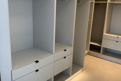 Inspiration for a modern walk-in wardrobe in Hampshire with flat-panel cabinets, grey cabinets, carpet and feature lighting.