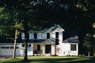 Large country white two-story concrete fiberboard and board and batten exterior home photo in Grand Rapids with a mixed material roof and a black roof