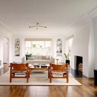 Diseño de salón mediterráneo con suelo de madera oscura, marco de chimenea de yeso y paredes blancas