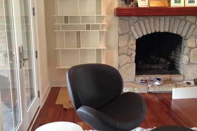 Example of a mid-sized minimalist enclosed dark wood floor living room design in Detroit with beige walls, a standard fireplace and a stone fireplace