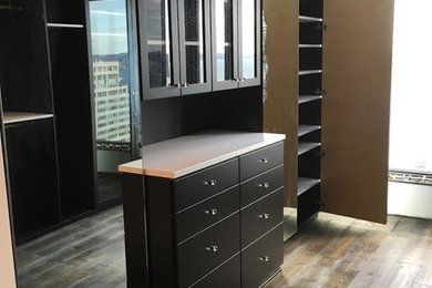 Large trendy gender-neutral medium tone wood floor walk-in closet photo in Seattle with flat-panel cabinets and black cabinets