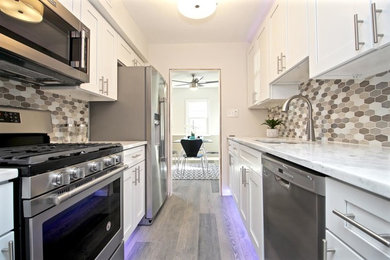 Small transitional galley laminate floor and gray floor eat-in kitchen photo in Wilmington with an undermount sink, shaker cabinets, white cabinets, quartz countertops, gray backsplash, mosaic tile backsplash and stainless steel appliances