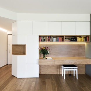 Inspiration for a medium sized modern home office and library in Milan with a reading nook, white walls, light hardwood flooring, beige floors and a built-in desk.