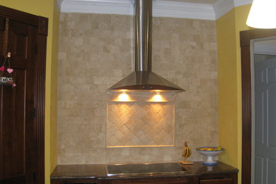 Example of a mid-sized classic galley medium tone wood floor and brown floor eat-in kitchen design in Other with raised-panel cabinets, brown cabinets, granite countertops, beige backsplash, stainless steel appliances, an undermount sink and stone tile backsplash