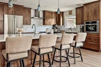 Eat-in kitchen - large transitional l-shaped light wood floor and brown floor eat-in kitchen idea in Denver with an undermount sink, flat-panel cabinets, medium tone wood cabinets, quartzite countertops, white backsplash, ceramic backsplash, stainless steel appliances, an island and white countertops